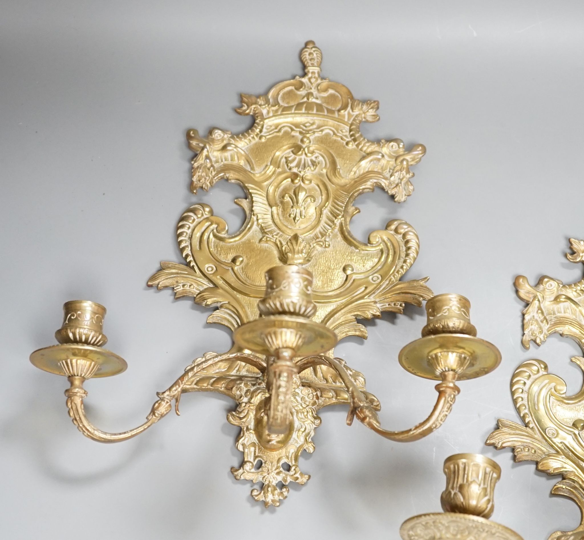 A pair of French ornate brass three branch wall sconces, 37 cms high